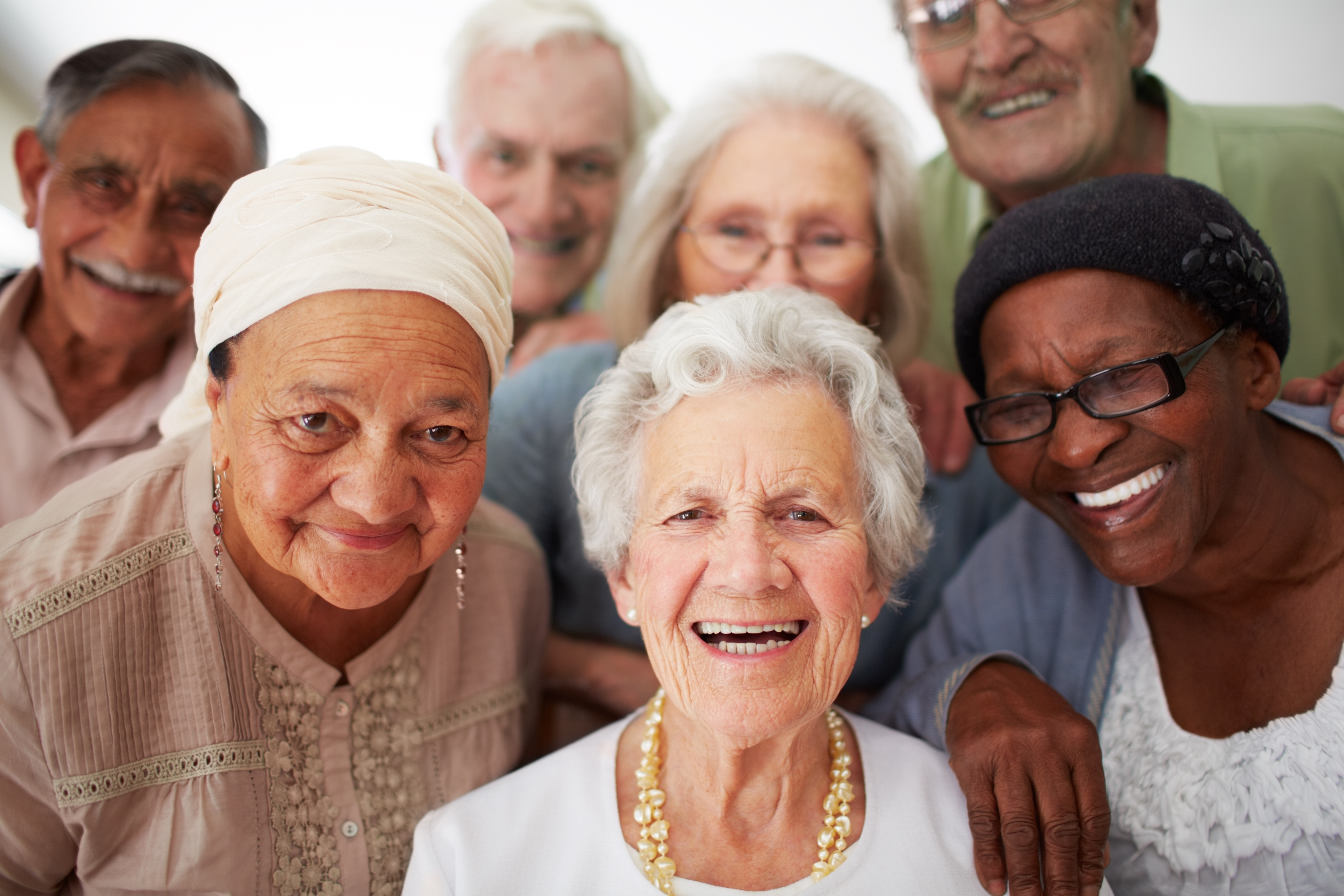 Smiling group of elderly friends, close together.