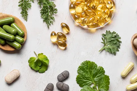 Herbal supplements and capsules on a light surface with green leaves.