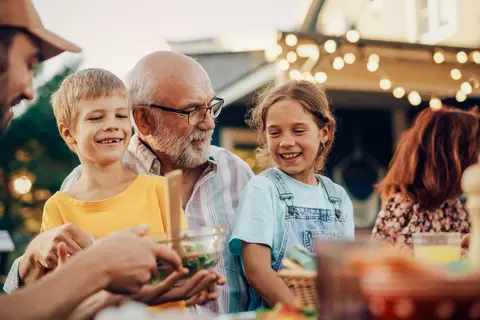 Family enjoying an outdoor meal, smiling warmly.