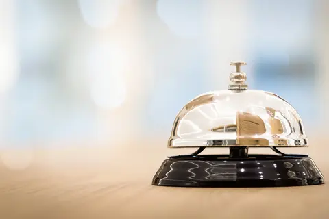 Service bell on wooden counter, blurred background.