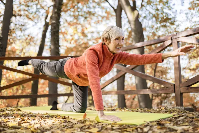 Woman doing yoga on a mat in an autumn forest.