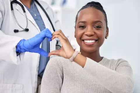 Doctor and smiling patient form a heart with hands.