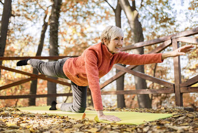 Woman doing yoga on a mat in an autumn forest.