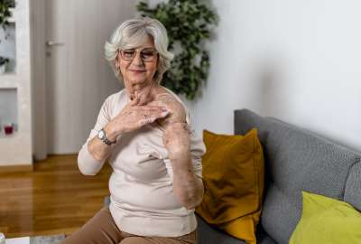 An older woman putting on a hormone cream on her shoulder