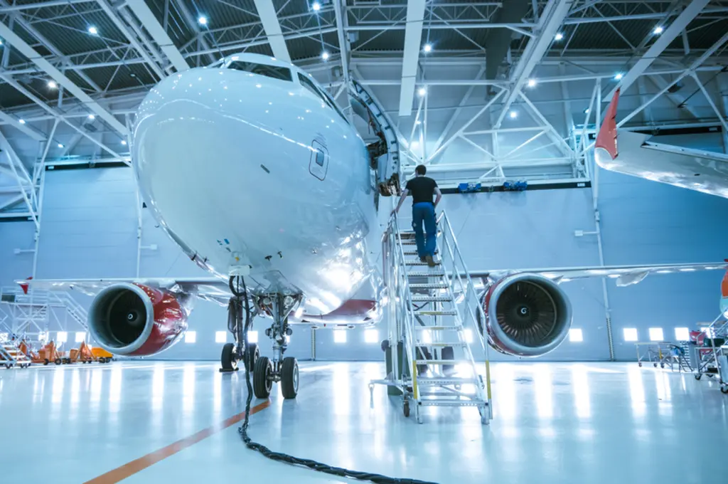 Aircraft in hangar with technician on a ladder.