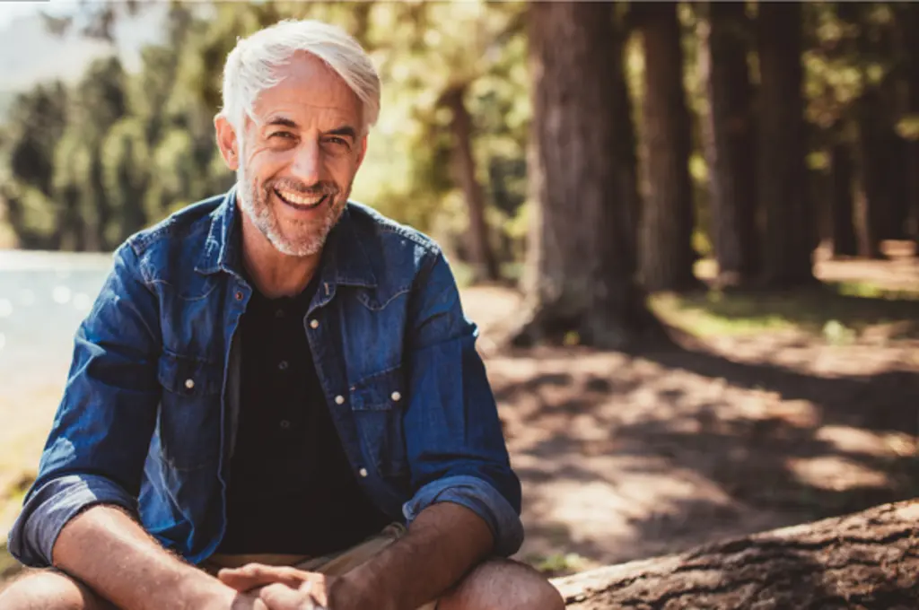 Healthy man sits by a lake enjoying a carefree afternoon of good health