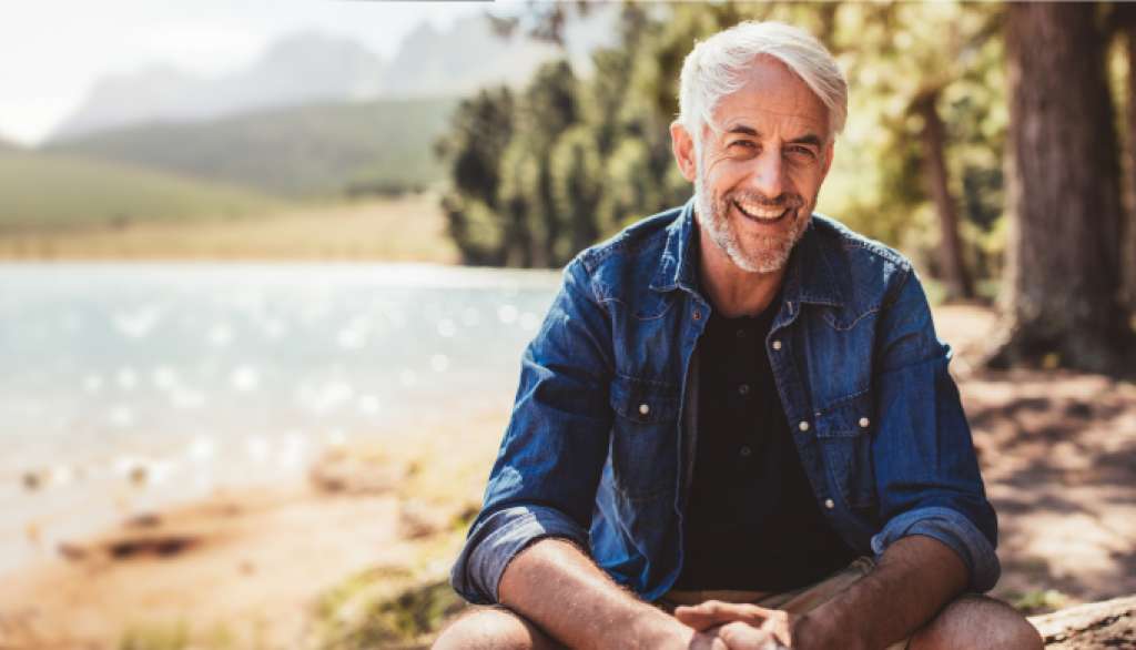 Healthy man sits by a lake enjoying a carefree afternoon of good health