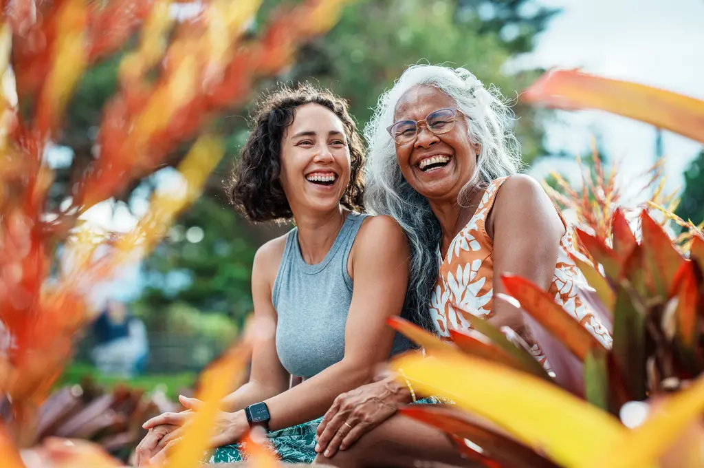 Happy, healthy woman laughing together in a garden surrounded by colorful plants and flowers