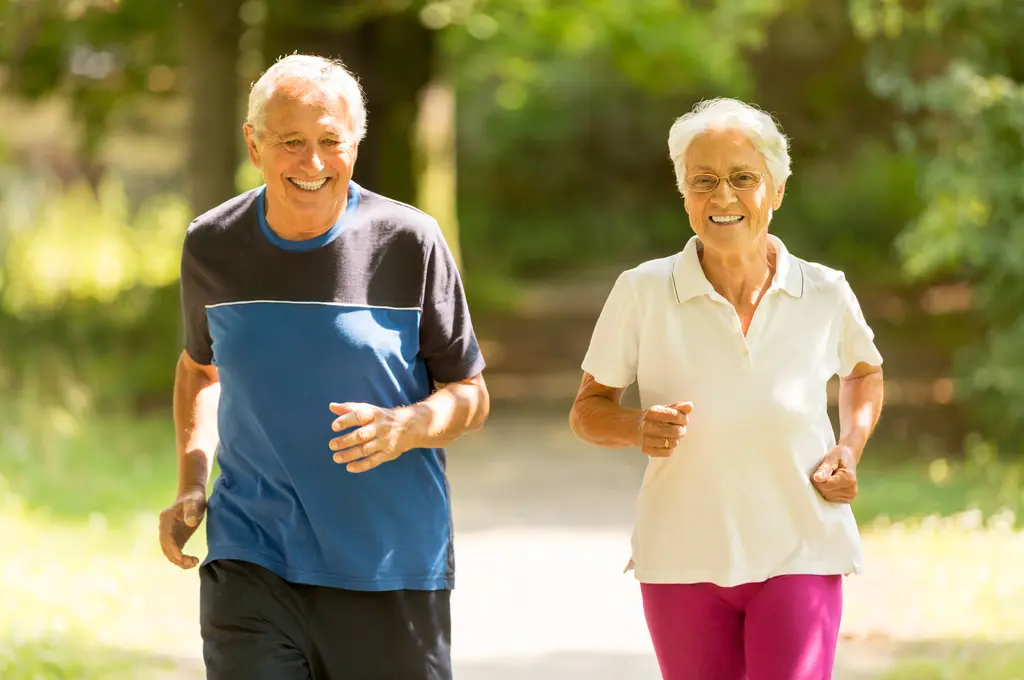 Elderly couple jogging outdoors, smiling brightly.