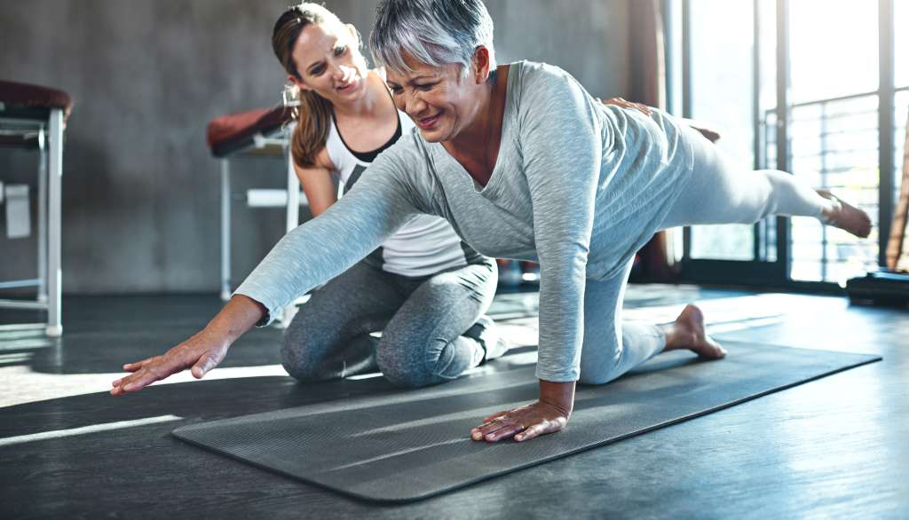 Woman doing yoga stretch with instructor guiding her.