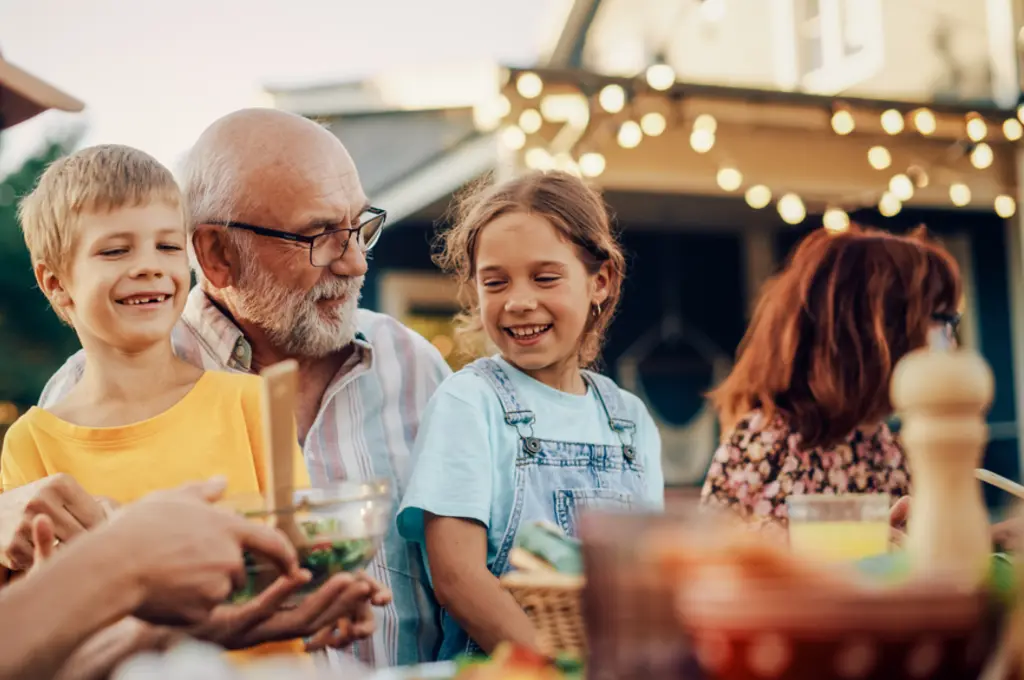 Family enjoying an outdoor meal, smiling warmly.
