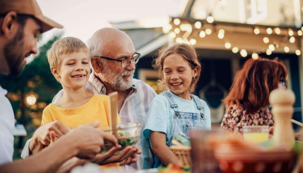 Family enjoying an outdoor meal, smiling warmly.
