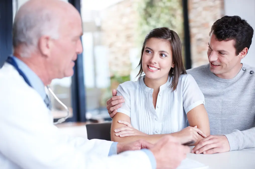 Doctor talking with a smiling couple.