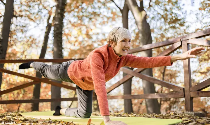 Woman doing yoga on a mat in an autumn forest.
