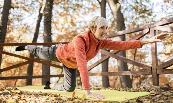 Woman doing yoga on a mat in an autumn forest.