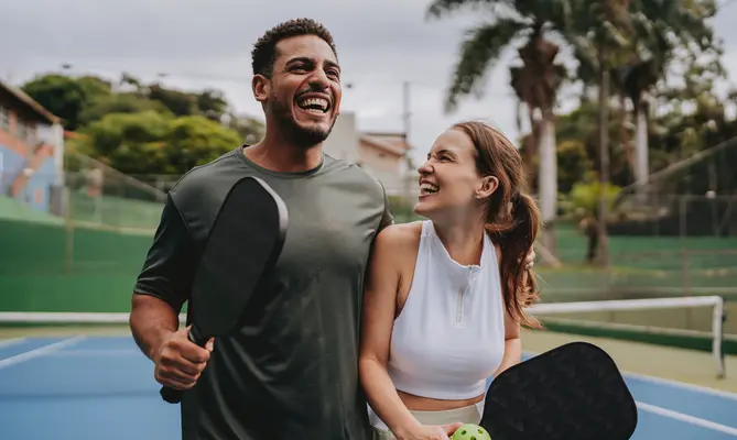 Young professional couple laughing and playing pickleball