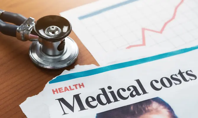 Stethoscope on table with rising medical costs graph.