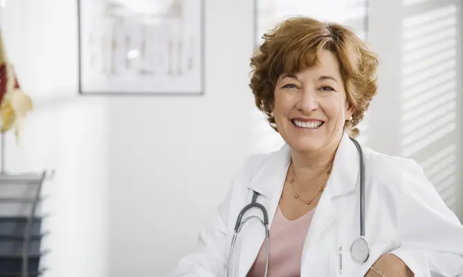 Smiling doctor with a stethoscope in an office setting.