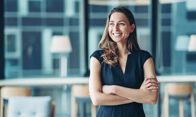 Smiling woman with crossed arms in a modern office.