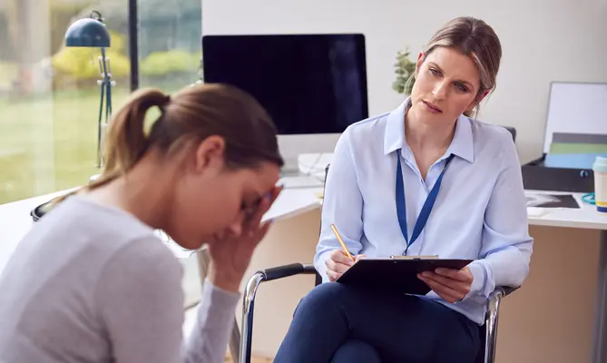 Therapist listens to a distressed woman in an office setting.
