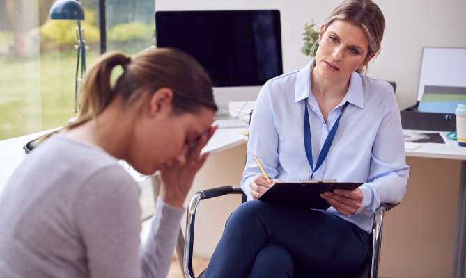 Therapist listens to a distressed woman in an office setting.