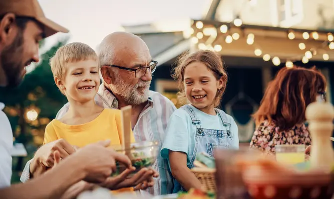 Family enjoying an outdoor meal, smiling warmly.