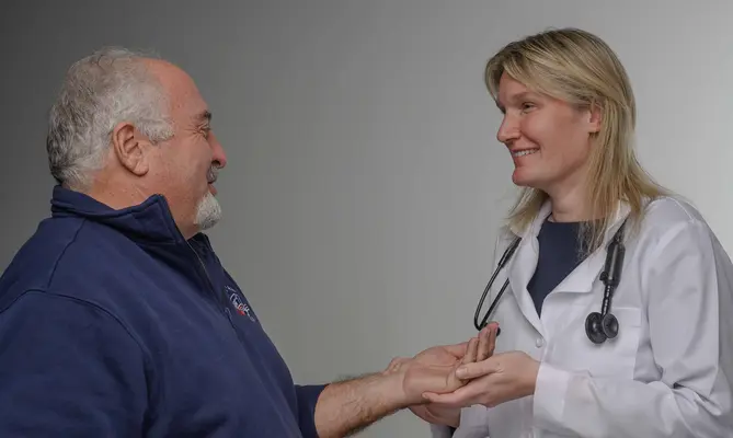 Dr. Kate Shoemaker smiling while holding a patient's hand.