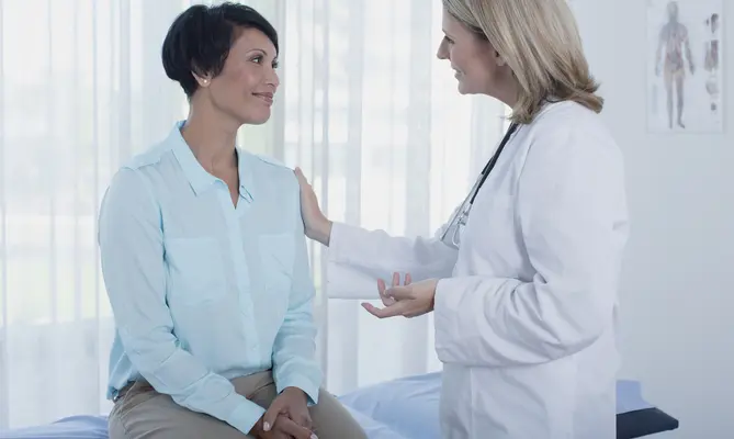A patient in discussion with a doctor in a bright examination room