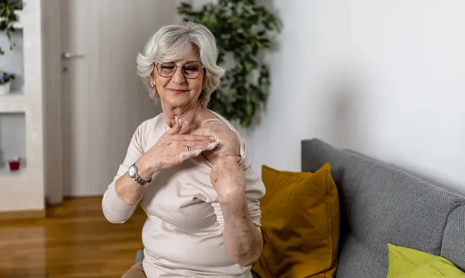 An older woman putting on a hormone cream on her shoulder