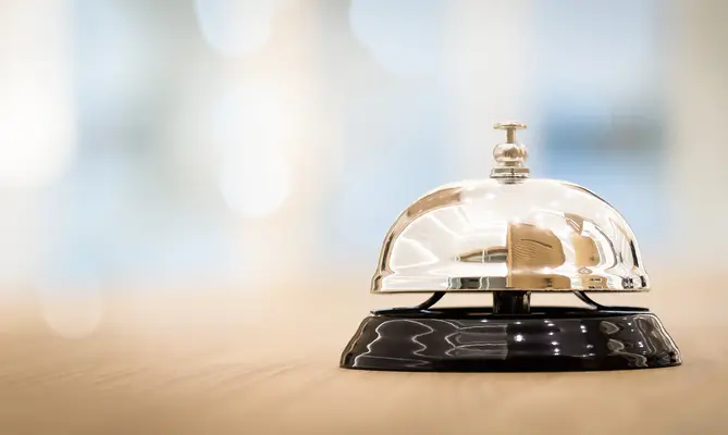 Service bell on wooden counter, blurred background.