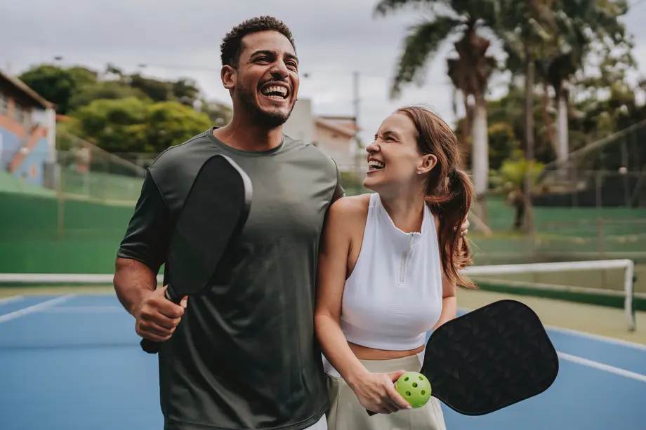 Young professional couple laughing and playing pickleball