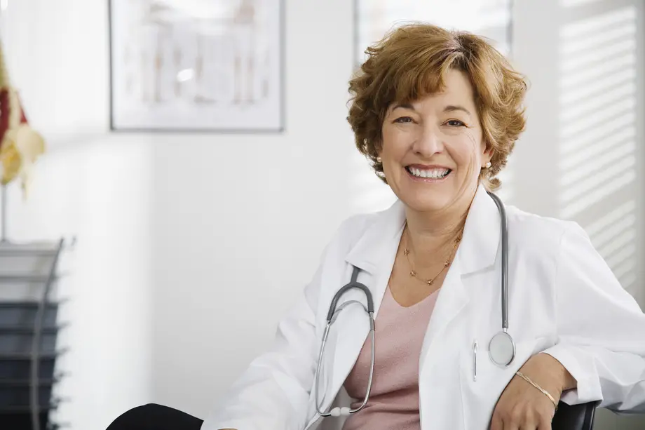 Smiling doctor with a stethoscope in an office setting.