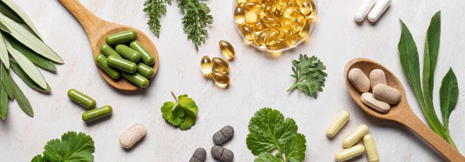 Herbal supplements and capsules on a light surface with green leaves.