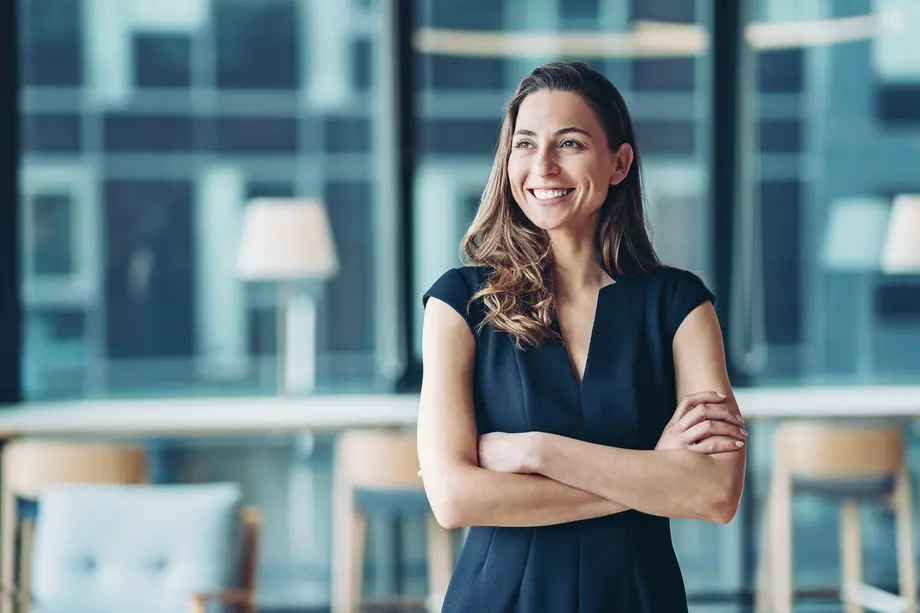 Smiling woman with crossed arms in a modern office.