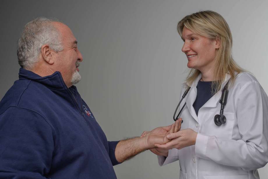 Dr. Kate Shoemaker smiling while holding a patient's hand.