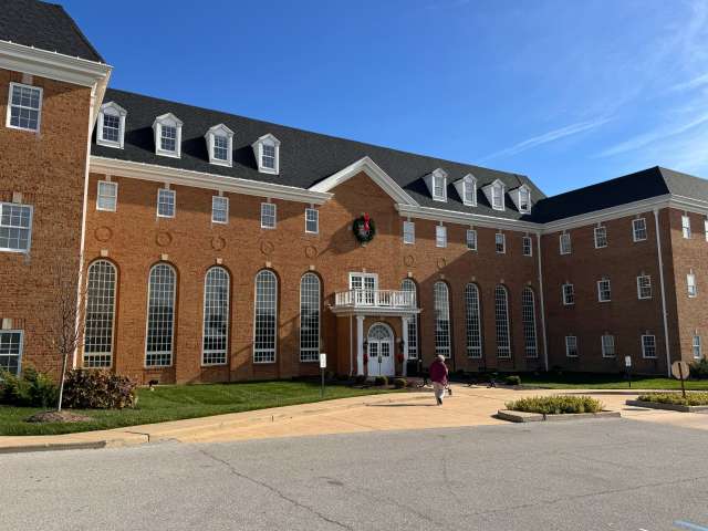 Red-brick building with tall windows and wreath, under a clear blue sky.