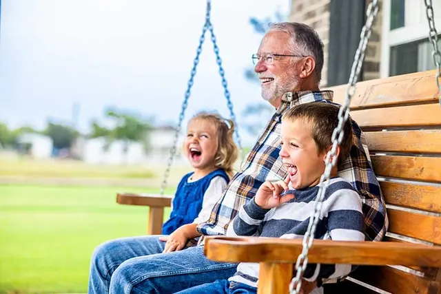Grandfather enjoying an afternoon on a swing with his two grandkids
