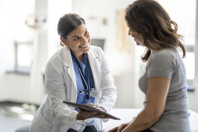 Doctor smiling while talking to a patient in an examination room.