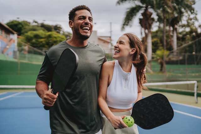 Young professional couple laughing and playing pickleball