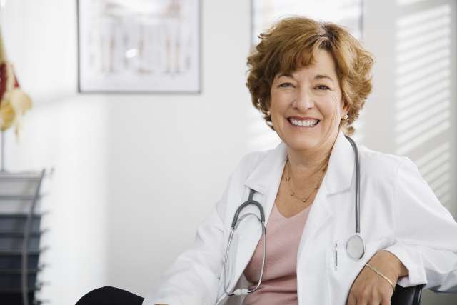 Smiling doctor with a stethoscope in an office setting.