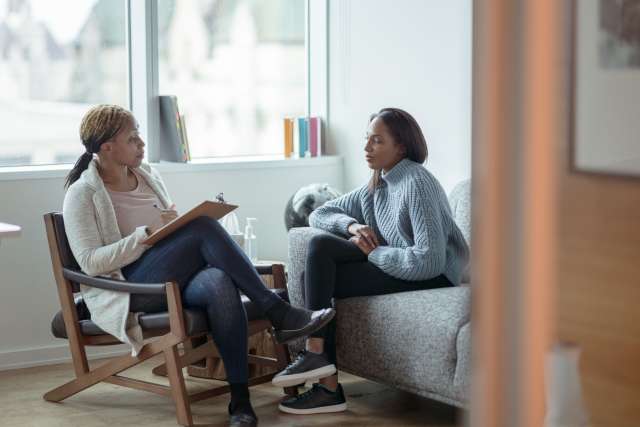 Two women in a therapy session, seated facing each other.