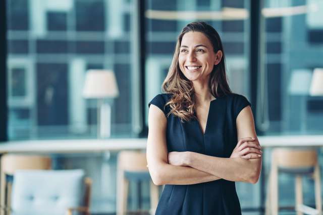 Smiling woman with crossed arms in a modern office.