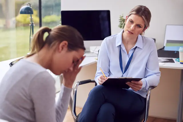 Therapist listens to a distressed woman in an office setting.