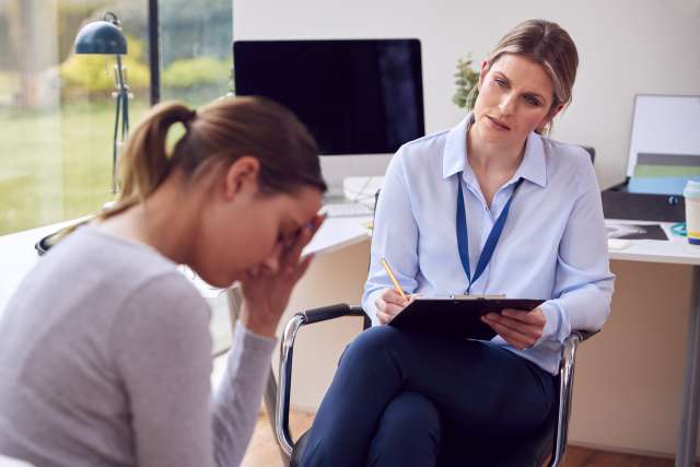 Therapist listens to a distressed woman in an office setting.