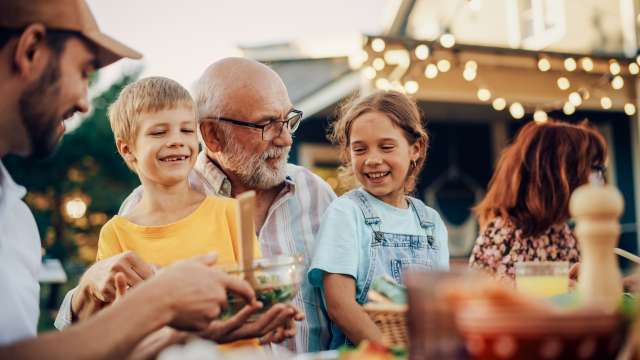 Family enjoying an outdoor meal, smiling warmly.