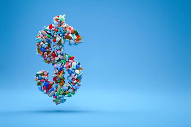 Dollar sign made of colorful pills on a blue background.
