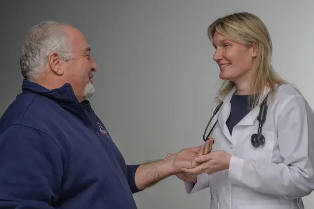 Dr. Kate Shoemaker smiling while holding a patient's hand.