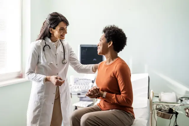 A doctor and a female patient smiling and talking to each other