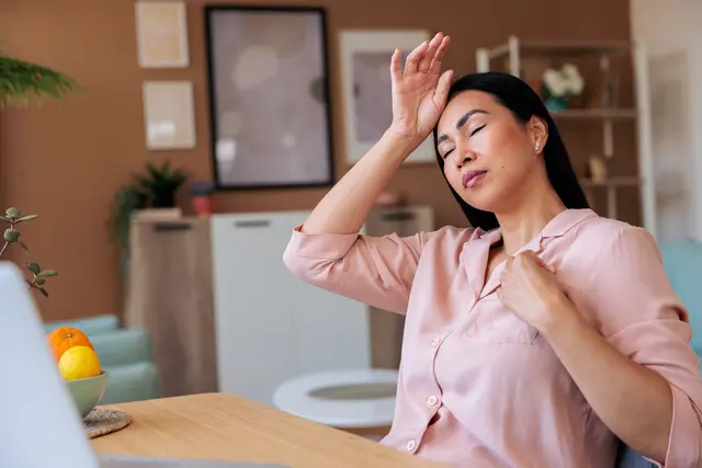 A middle aged woman who appears uncomfortably warm