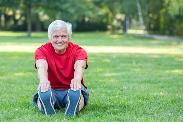 An older man stretching in the park